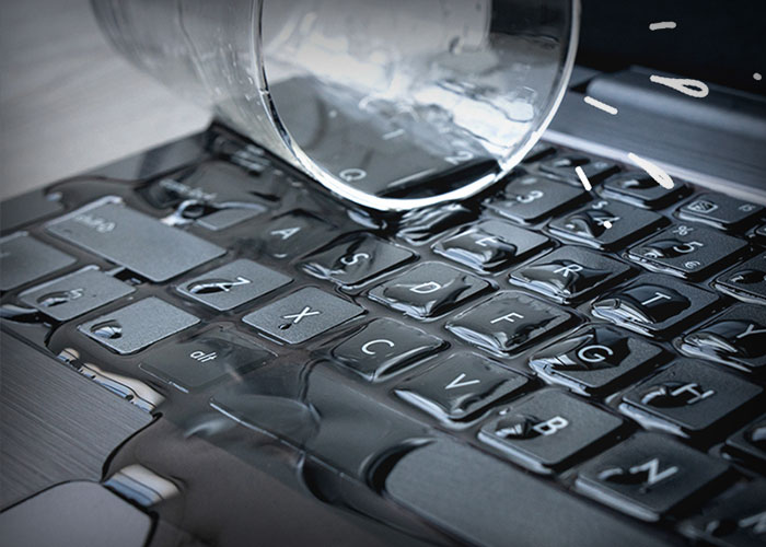 Glas med vand ud over tastatur